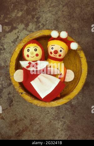 Ancienne assiette en bois jaune contenant deux marionnettes une femelle gaie l'autre femelle anxieux Banque D'Images