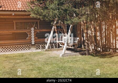 Patio avec grande balançoire en bois devant une maison moderne en bois. Solide cottage en bois pour un séjour confortable et la vie en dehors de la ville. Banque D'Images