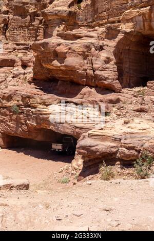 Pick-up garés à l'ombre d'une grotte sculptée dans une grande formation de roche de grès Banque D'Images