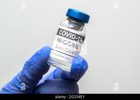 Flacon de vaccin COVID-19 sur fond blanc, flacon de vaccin coronavirus dans la main gantée du médecin. Concept de médecine, vaccination, vaccination, Banque D'Images