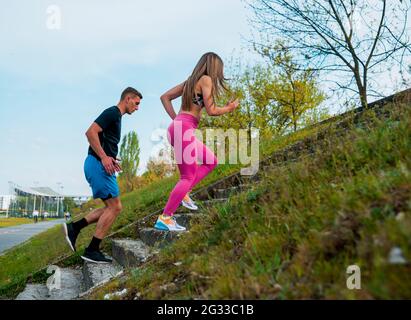 Jeune couple de sportifs en forme garçon et fille courant tout en faisant de l'exercice à l'extérieur Banque D'Images