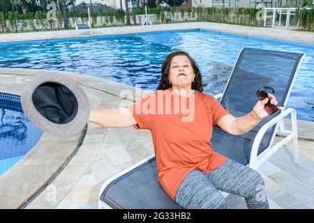 femme âgée de 74 ans au bord de la piscine, heureuse de sa retraite. Banque D'Images