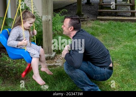 Lynwood, Washington, États-Unis. Homme parlant à sa fille de 4 ans qui est dans son oscillation. (M.) Banque D'Images