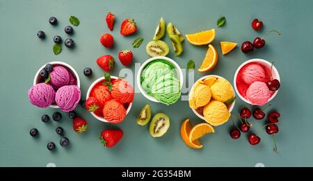 Saveurs gastronomiques de crème glacée italienne servies dans des gobelets individuels en papier glacé sur fond bleu. Sorbet aux fraises, glace aux myrtilles et orange Banque D'Images