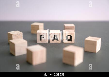 FAQ écrite sur des blocs de bois sur fond gris foncé. Concept de questions fréquemment posées. Banque D'Images