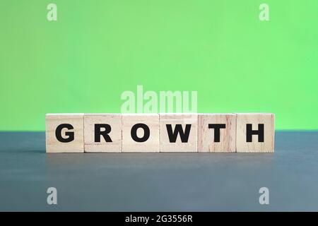 Lettres de texte de croissance sur cube en bois avec fond vert. Banque D'Images
