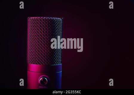 Microphone studio sur fond sombre avec espace de copie. Microphone à condenser professionnel noir avec néon. Enregistrement de podcast Banque D'Images