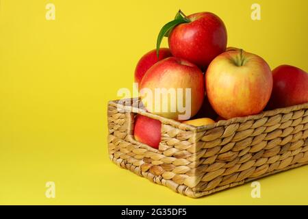 Panier avec pommes rouges sur fond jaune Banque D'Images