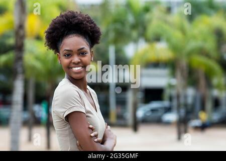 Bonne rigolante femme des caraïbes avec des cheveux afro et un espace de copie en plein air en été dans la ville Banque D'Images