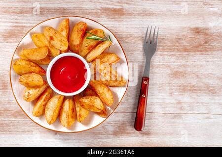 Quartiers de pommes de terre cuits avec une fourchette et un endroit pour le texte, tiré du dessus sur un fond rustique en bois Banque D'Images