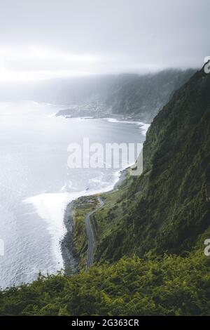 Nuages sur la route côtière entourée d'une végétation luxuriante de montagnes, Seixal, île de Madère, Portugal Banque D'Images