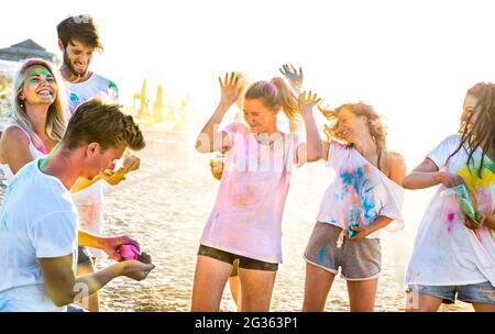 Des amis heureux s'amuser à la fête sur la plage en holi couleurs festival d'été - jeunes millénaires jouant avec une ambiance excitée authentique Banque D'Images