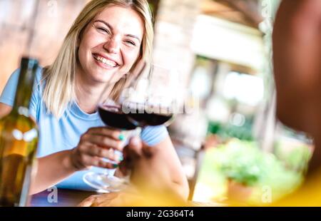 Une récolte de couple joyeux qui toaster le vin rouge au restaurant Countryside - nourriture et boissons concept de vie avec petit ami et petite amie Banque D'Images