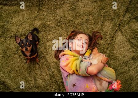 Adolescente à la maison en pyjama sur un écossais vert avec un chiot Chihuahua blanc et un Chihuahua noir. Banque D'Images