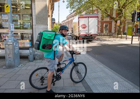 Uber mange un liveur à emporter sur un vélo qui attend à un passage piéton dans le centre-ville de norwich Banque D'Images