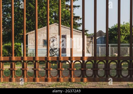 Foyer sélectif de clôture de cimetière en métal rouillé. Grande pierre de pierre et petite maison en arrière-plan. Filtre vintage. Souvenirs ou concept de perte. Banque D'Images