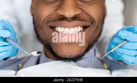 Prise de vue rognée d'un patient masculin noir souriant se faire traiter à la clinique Stomatologic Banque D'Images