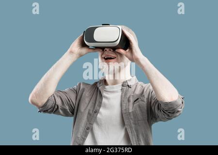 Jouer à des applications de jeux mobiles sur l'appareil. Albino homme expérience de la réalité virtuelle en VR lunettes, fond turquoise Banque D'Images