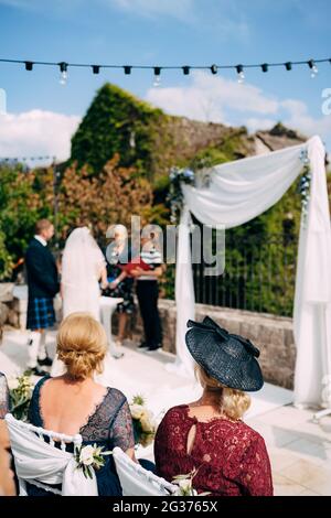 Cérémonie de mariage avec une mariée dans une robe de mariage, un marié dans une robe nationale écossaise et des invités dans de beaux vêtements Banque D'Images