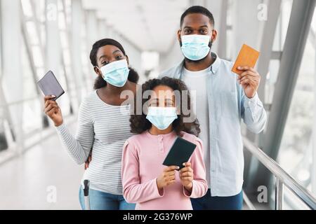 Famille noire dans les masques de voyage, la tenue de documents à l'aéroport Banque D'Images