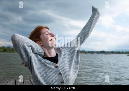 Jeune femme s'étendant heureusement, sur le lac, Starnberger See, haute-Bavière, Bavière, Allemagne Banque D'Images