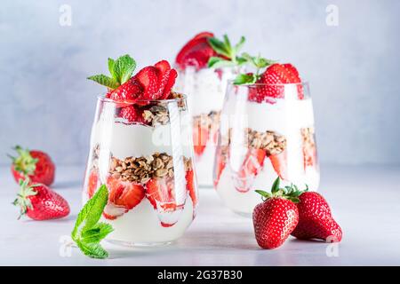 Petit déjeuner sain composé de parfaits aux fraises, de yaourts et de muesli frais en verres. Banque D'Images