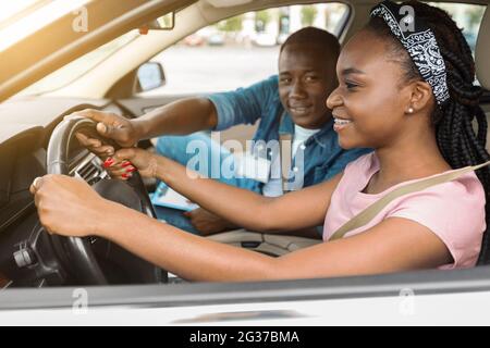 Bonne femme afro-américaine fréquentant l'école de conduite, conduisant avec un autocar Banque D'Images