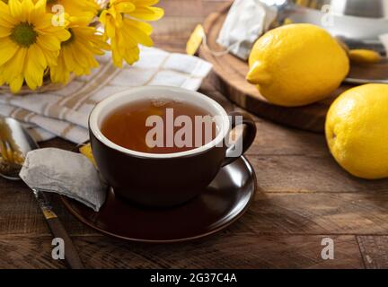 Cloeup d'une tasse de thé avec des citrons et des fleurs sur une table en bois Banque D'Images