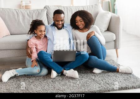 Bonne famille noire utilisant un ordinateur portable dans le salon Banque D'Images