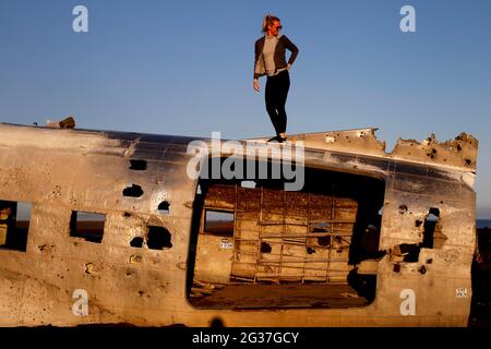 Femme grimpant sur l'épave de l'avion, US Navy Douglas DC-3, Sander, Solheimasandur, côte sud, Islande Banque D'Images