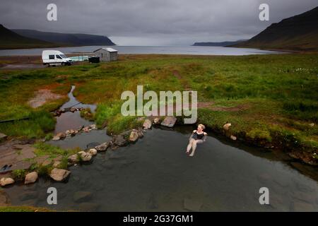 Piscine naturelle au fjord, hot pot, source géothermique, femme se baignant Reykjafjaroarlaug, Vestfiroir, Westfjords, Islande Banque D'Images