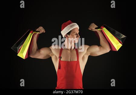 FIT santa claus tenir des sacs d'achats flexion des bras musclés biceps triceps préparation de noël, forte Banque D'Images