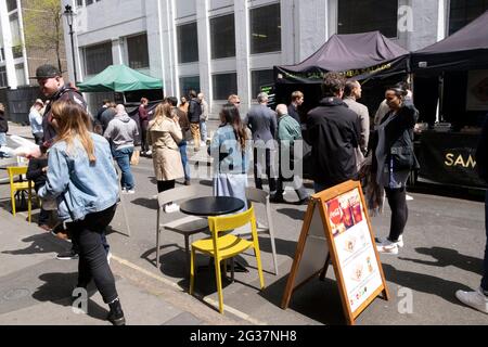 Les gens ont pris des distances sociales tout en faisant la queue pour manger dans un stand dans Leather Lane Street Market London EC1 England UK KATHY DEWITT Banque D'Images