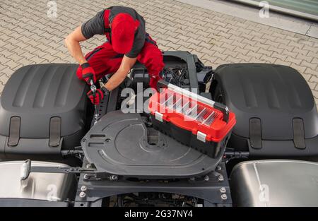 Mécanicien de camions caucasien professionnel dans ses années 40 effectuant l'entretien de véhicule. Tracteur semi-remorque à cheval Banque D'Images