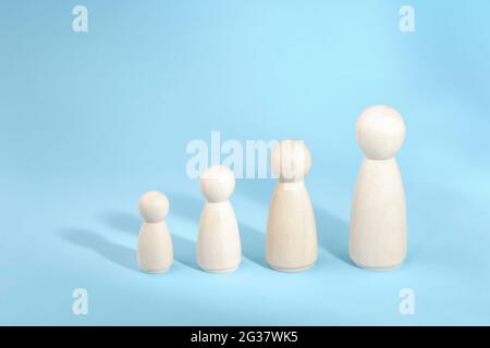 Figurines en bois debout dans une rangée de bas à haut. Croissance de la personne sur fond bleu. Banque D'Images