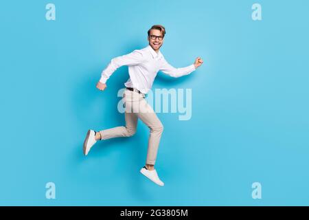 Vue sur toute la longueur du corps attrayant gai heureux homme saut courir bonne humeur isolée sur fond bleu clair de couleur Banque D'Images