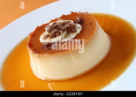 Crème caramel à la banane décorée de tranches de banane et de copeaux de chocolat. Banque D'Images