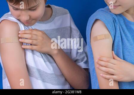 Garçons avec pansement adhésif sur leurs bras après la vaccination. Injection vaccin covid, soins de santé pour les enfants et les adolescents Banque D'Images