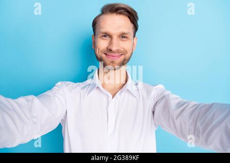 Photo de charmant heureux positif jeune homme main appareil photo faire selfie isolé sur fond bleu de couleur Banque D'Images