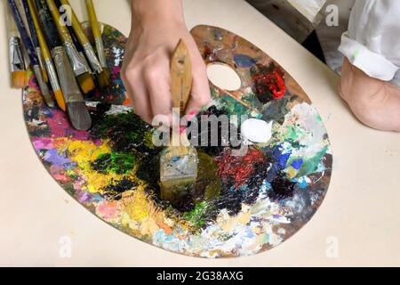 Le peintre féminin créatif mélange une palette de peintures à l'huile dans une palette. Vue rapprochée. Photo de haute qualité Banque D'Images