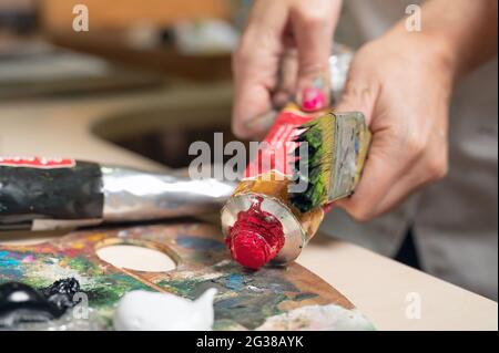 Le peintre féminin créatif mélange une palette de peintures à l'huile dans une palette. Vue rapprochée. Photo de haute qualité Banque D'Images