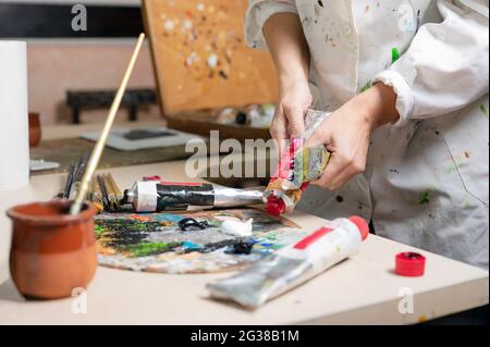 Le peintre féminin créatif mélange une palette de peintures à l'huile dans une palette. Vue rapprochée. Photo de haute qualité Banque D'Images
