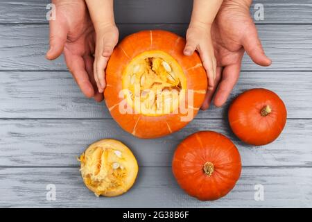 Mains d'une fille et d'un père qui tire les graines et le matériel fibreux d'une citrouille avant de sculpter pour Halloween. Décoration de fête. Peu d'aide. Vue Banque D'Images