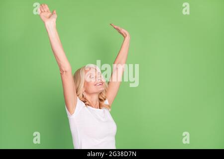 Photo portrait femme aînée souriante relaxante après une dure journée surjoyeuse isolée sur fond vert pastel Banque D'Images