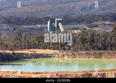 Photographie de convoyeurs de transport dans une grande collierie entourée de piles de charbon situées dans une forêt Banque D'Images