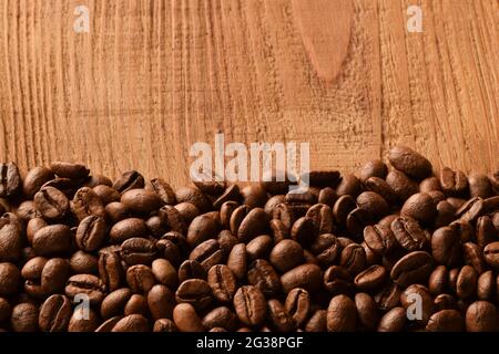 Saupoudrer les grains de café au bas de la photo. La moitié supérieure de la photo est un arrière-plan en bois marron vide Banque D'Images