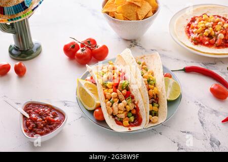 Composition avec tacos savoureux, nachos, sombrero et cactus en céramique sur fond clair Banque D'Images