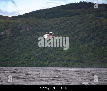 Dores, Loch Ness, Écosse, Royaume-Uni. 14 juin 2021. Photo : hélicoptère de la Garde côtière survolant les eaux profondes et sombres du Loch Ness, où de nombreuses observations de monstres du Loch Ness ont été faites depuis la plage de Dimes. L'hélicoptère est vu descendre le personnel dans le loch pour effectuer un sauvetage en eau depuis la plate-forme aérienne tout en planant à moins de cent pieds au-dessus de la surface de l'eau. Crédit : Colin Fisher/Alay Live News Banque D'Images