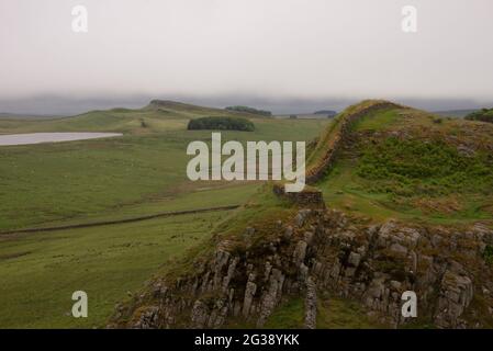 Vestiges du mur d'Hadrien, l'ancien mur-frontière romain traversant le nord de l'Angleterre, alors qu'ils serpentent à travers les collines à l'ouest du fort romain Housesteads. Longeant l'ensemble du site classé au patrimoine mondial de l'UNESCO, le chemin du mur d'Hadrien est l'un des sentiers de randonnée les plus populaires d'Angleterre. Banque D'Images