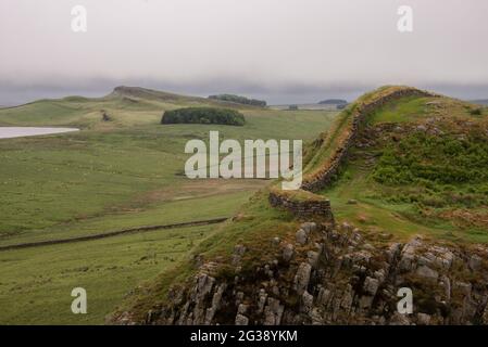 Vestiges du mur d'Hadrien, l'ancien mur-frontière romain traversant le nord de l'Angleterre, alors qu'ils serpentent à travers les collines à l'ouest du fort romain Housesteads. Longeant l'ensemble du site classé au patrimoine mondial de l'UNESCO, le chemin du mur d'Hadrien est l'un des sentiers de randonnée les plus populaires d'Angleterre. Banque D'Images